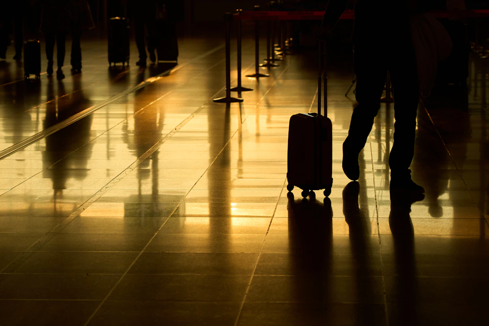 Viajante com mala em um terminal de aeroporto iluminado ao entardecer